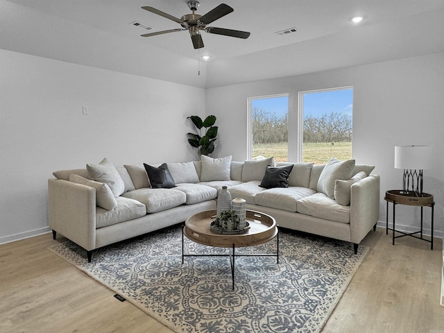 living room with ceiling fan, lofted ceiling, and light wood-type flooring