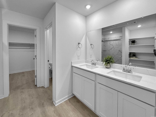 bathroom with hardwood / wood-style floors, vanity, a shower with shower door, and toilet