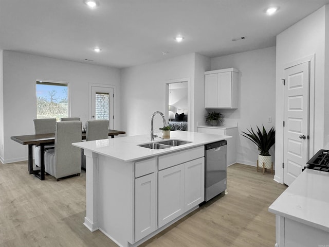 kitchen with stainless steel dishwasher, sink, white cabinets, and an island with sink