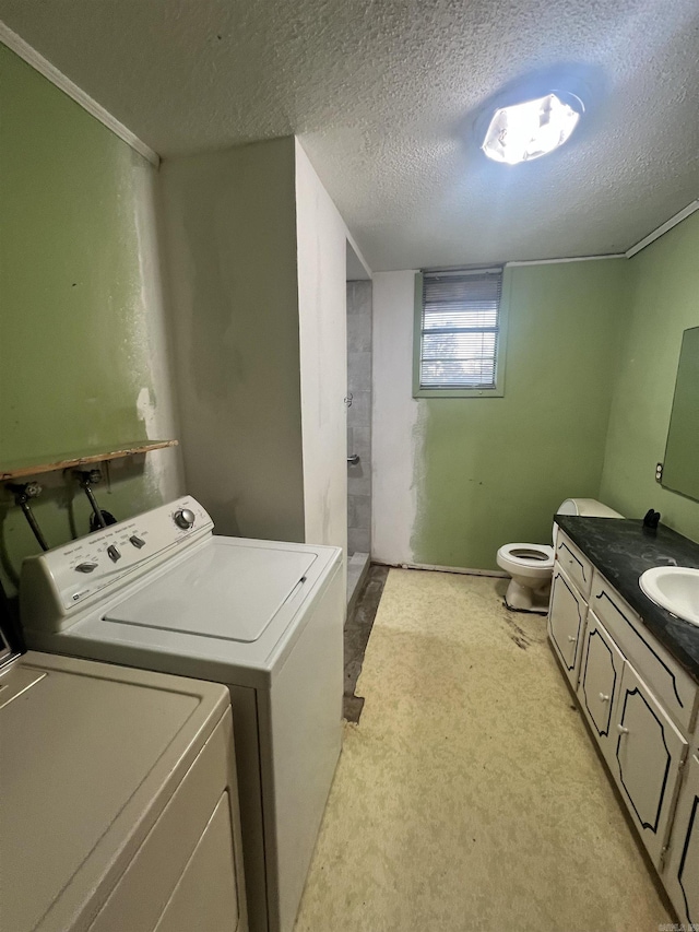 washroom with sink, independent washer and dryer, and a textured ceiling