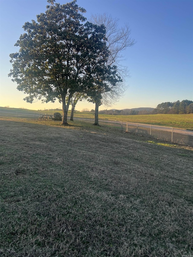 yard at dusk featuring a rural view