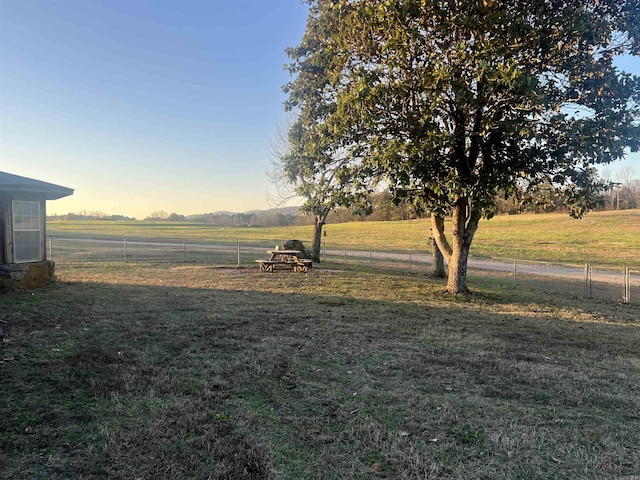 yard at dusk featuring a rural view