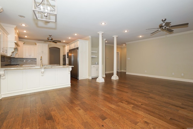 kitchen featuring light stone countertops, white cabinetry, dark hardwood / wood-style floors, crown molding, and stainless steel built in fridge