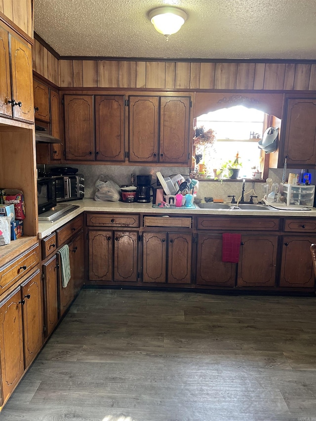 kitchen with dark hardwood / wood-style flooring, sink, wooden walls, and a textured ceiling