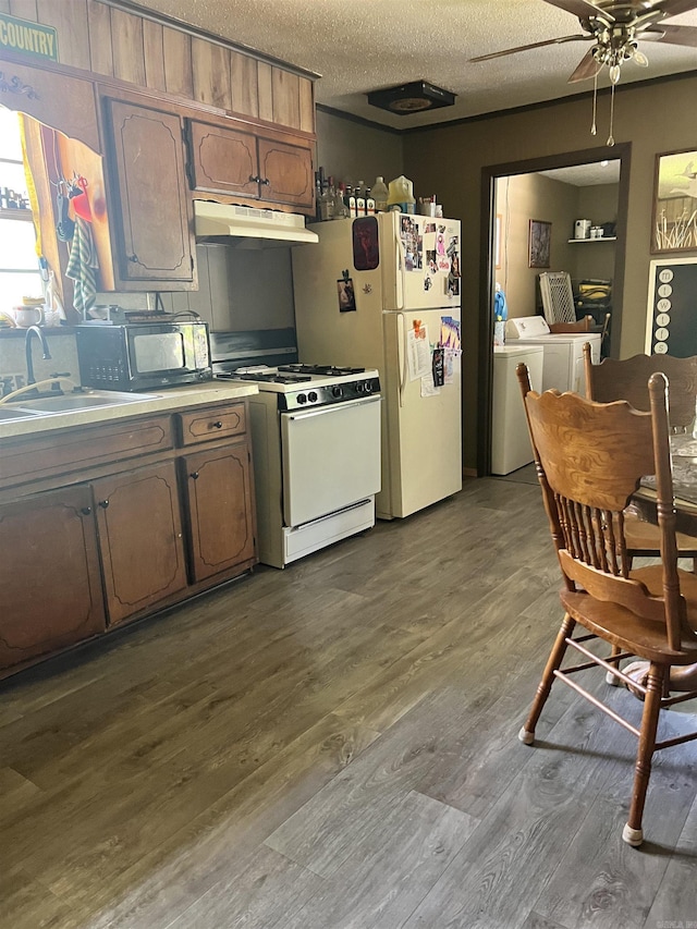 kitchen with sink, a textured ceiling, light hardwood / wood-style flooring, white appliances, and washing machine and dryer