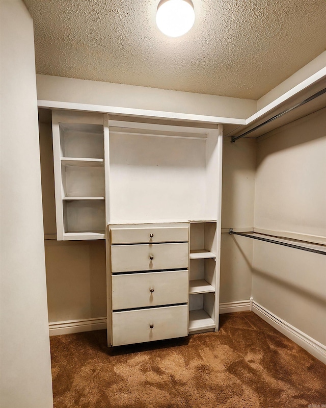 walk in closet featuring dark carpet