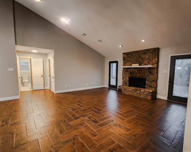 unfurnished living room with dark parquet flooring, a fireplace, and vaulted ceiling