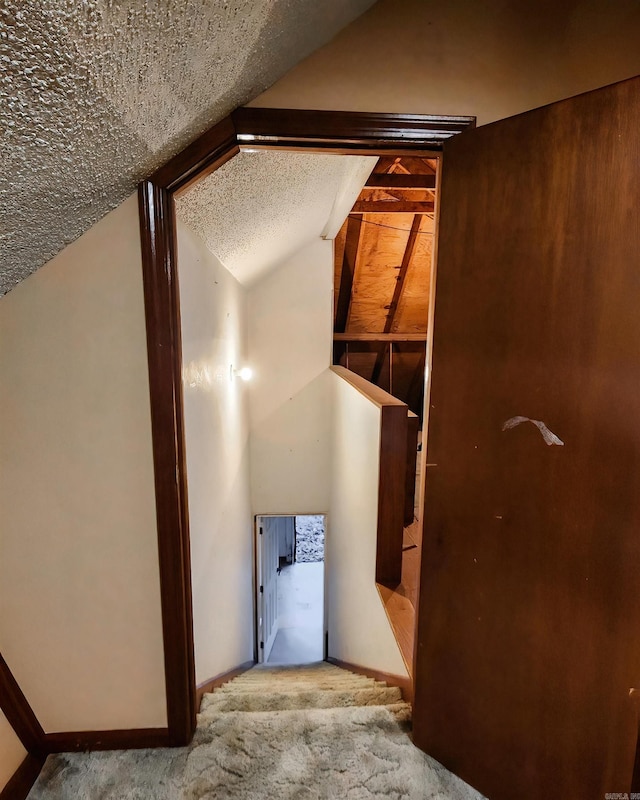 hallway with a textured ceiling, light carpet, and lofted ceiling