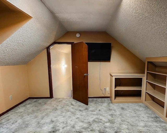 additional living space featuring lofted ceiling, a textured ceiling, and light carpet