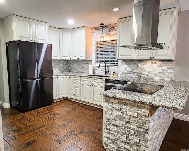 kitchen featuring sink, wall chimney range hood, kitchen peninsula, fridge, and white cabinets