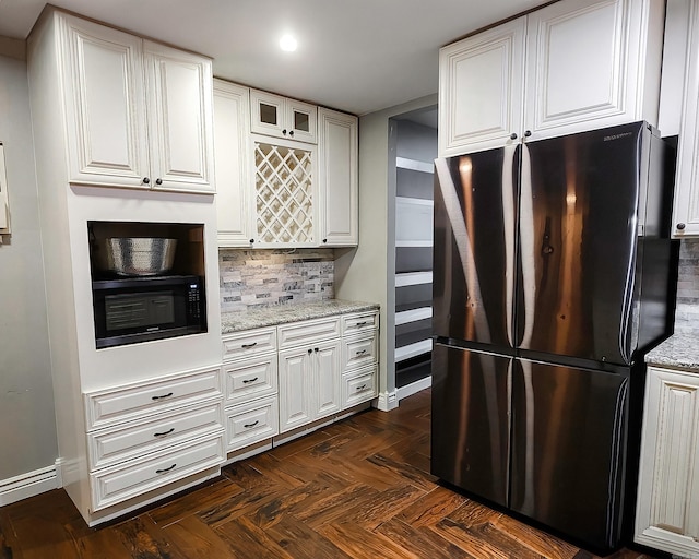 kitchen featuring white cabinets, decorative backsplash, stainless steel fridge, and light stone counters