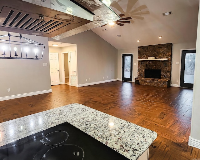 unfurnished living room featuring dark parquet floors, a stone fireplace, ceiling fan, and lofted ceiling