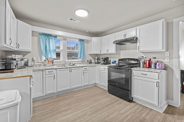 kitchen featuring light stone countertops, light wood-type flooring, sink, white cabinetry, and black / electric stove