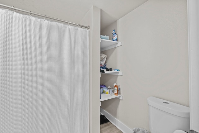 bathroom featuring hardwood / wood-style floors, toilet, and a shower with curtain