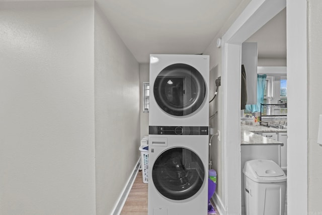 washroom with light hardwood / wood-style floors and stacked washing maching and dryer