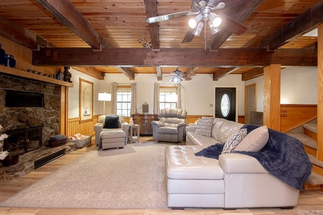 living room with beamed ceiling, light wood-type flooring, ceiling fan, and wooden walls