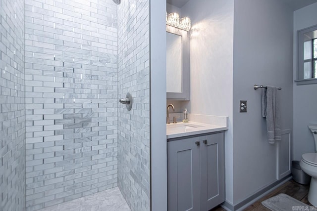 bathroom with tiled shower, vanity, and toilet