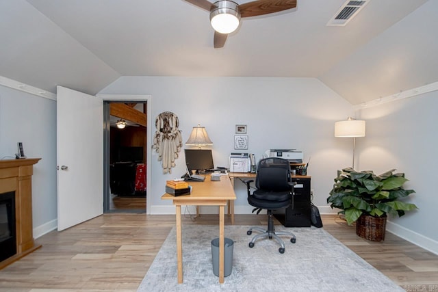 office area featuring ceiling fan, light wood-type flooring, a fireplace, and vaulted ceiling