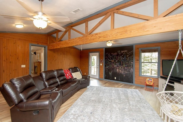 living room with wood walls, ceiling fan, lofted ceiling with beams, and light hardwood / wood-style floors