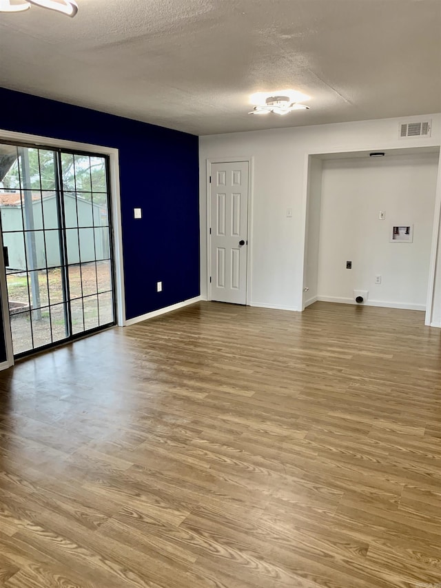 unfurnished room with a textured ceiling and light hardwood / wood-style floors