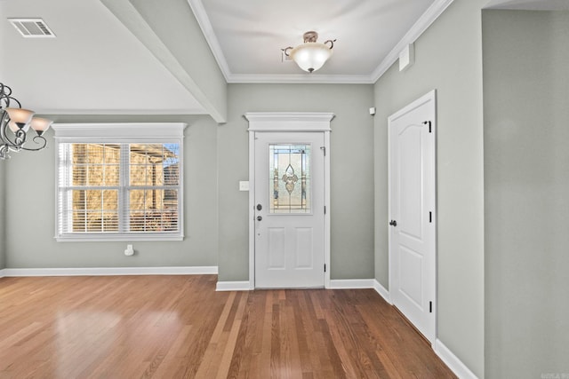 entrance foyer with a wealth of natural light, crown molding, hardwood / wood-style flooring, and a notable chandelier