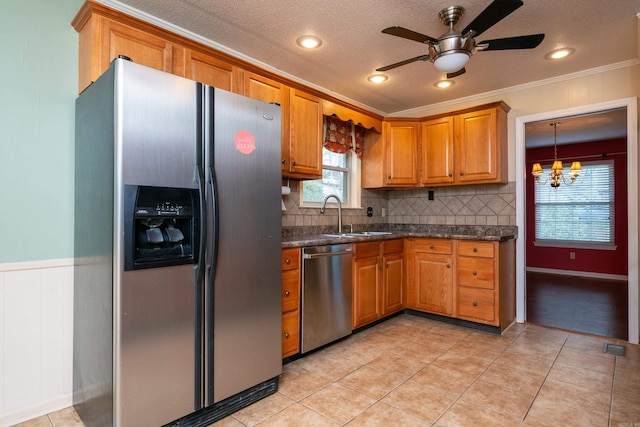 kitchen featuring sink, stainless steel appliances, decorative light fixtures, ceiling fan with notable chandelier, and ornamental molding