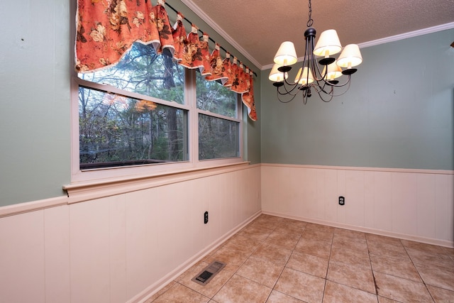 unfurnished dining area with crown molding, light tile patterned flooring, a textured ceiling, and a notable chandelier