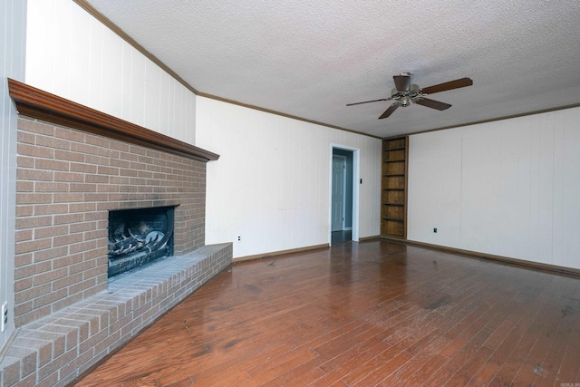 unfurnished living room featuring built in shelves, a textured ceiling, dark hardwood / wood-style floors, and a brick fireplace