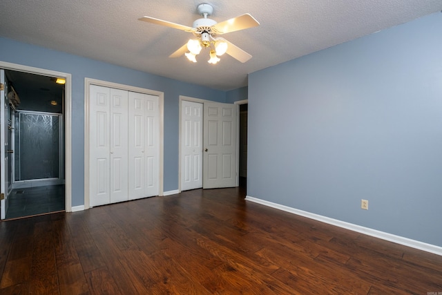 unfurnished bedroom with two closets, ceiling fan, dark hardwood / wood-style floors, and a textured ceiling