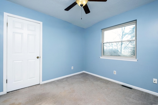 spare room with a textured ceiling, ceiling fan, and light carpet