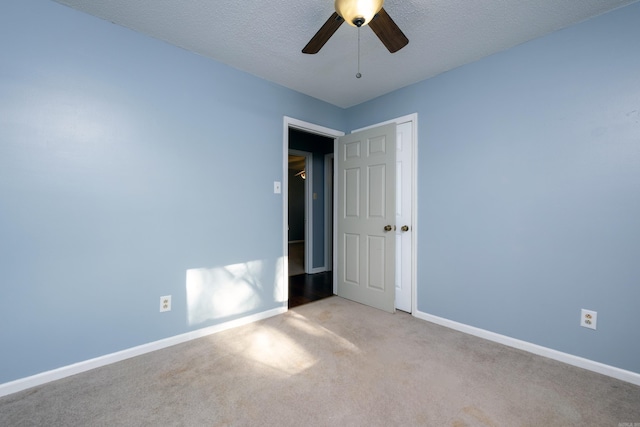 carpeted empty room with ceiling fan and a textured ceiling