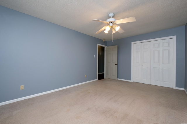 unfurnished bedroom with ceiling fan, a closet, light carpet, and a textured ceiling