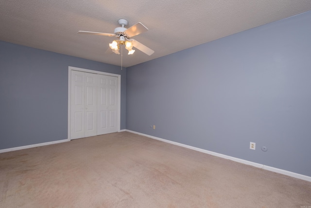 unfurnished bedroom with carpet flooring, a textured ceiling, a closet, and ceiling fan