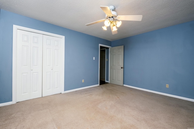 unfurnished bedroom with carpet flooring, ceiling fan, a textured ceiling, and a closet