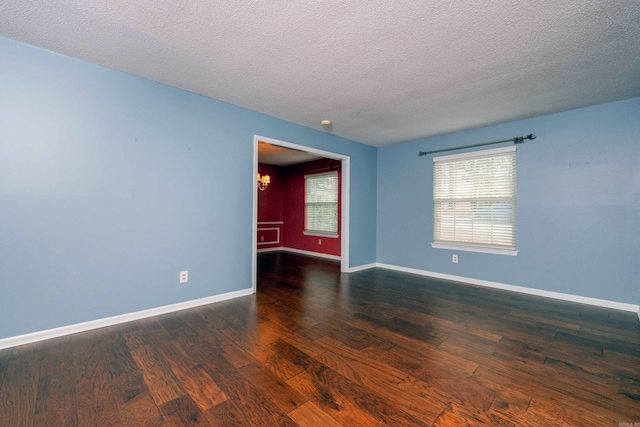 spare room with a textured ceiling, dark hardwood / wood-style floors, and a notable chandelier