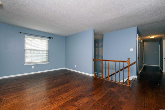 spare room with dark wood-type flooring and a textured ceiling