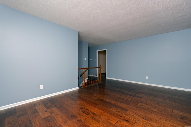 empty room with dark hardwood / wood-style flooring and a textured ceiling