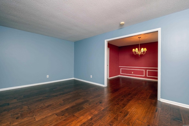 spare room featuring a textured ceiling, dark hardwood / wood-style floors, and a notable chandelier