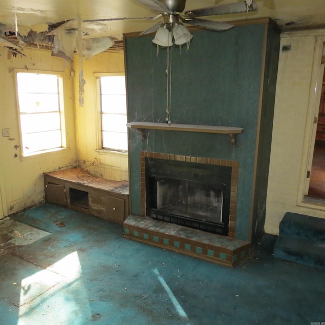 unfurnished living room featuring ceiling fan and a brick fireplace