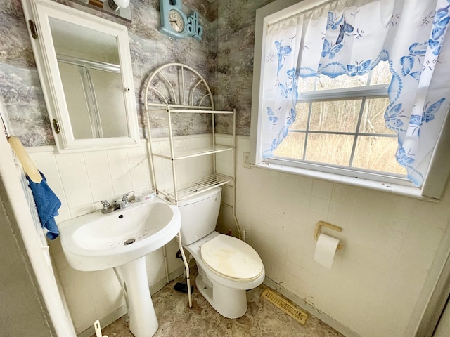 bathroom with sink, a shower with door, and toilet