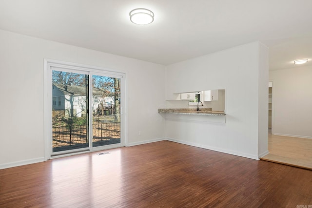 unfurnished living room with dark wood-type flooring and sink