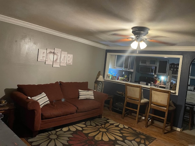 living room featuring hardwood / wood-style flooring, ceiling fan, and ornamental molding