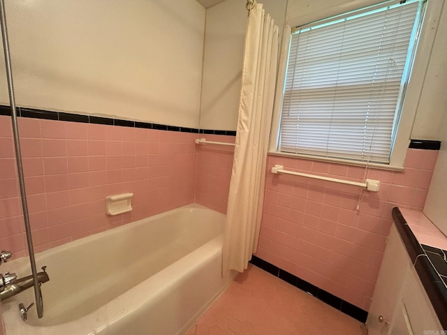 bathroom with shower / bath combination with curtain, tile patterned floors, and tile walls