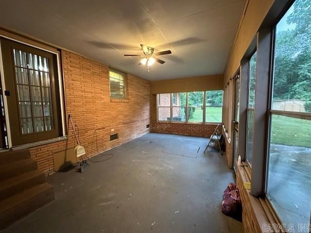 unfurnished sunroom featuring ceiling fan