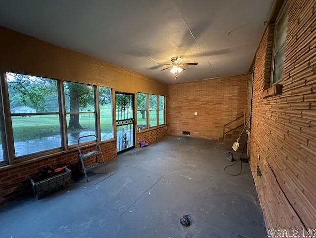 unfurnished sunroom featuring ceiling fan