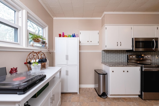 kitchen with white cabinets, ornamental molding, backsplash, and appliances with stainless steel finishes