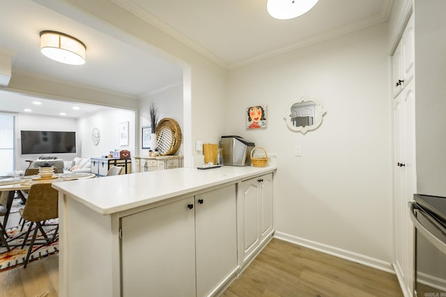 kitchen with white cabinets, light wood-type flooring, kitchen peninsula, and ornamental molding