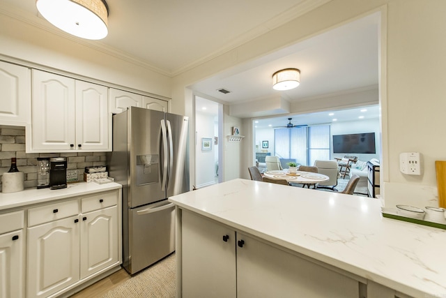 kitchen featuring decorative backsplash, stainless steel fridge with ice dispenser, white cabinets, and light stone counters