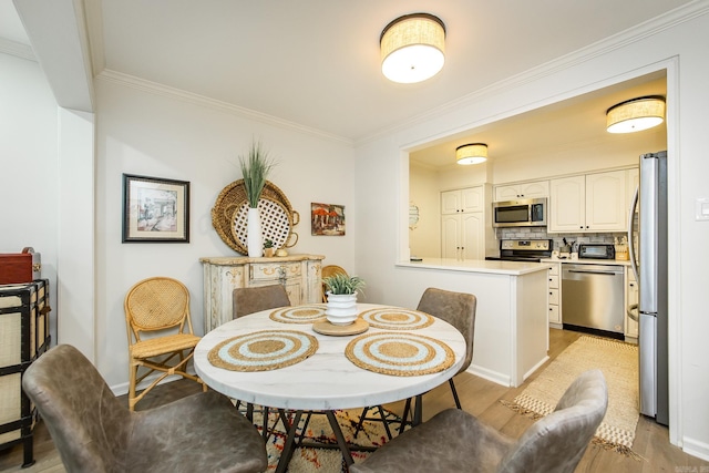 dining room with crown molding and light hardwood / wood-style floors