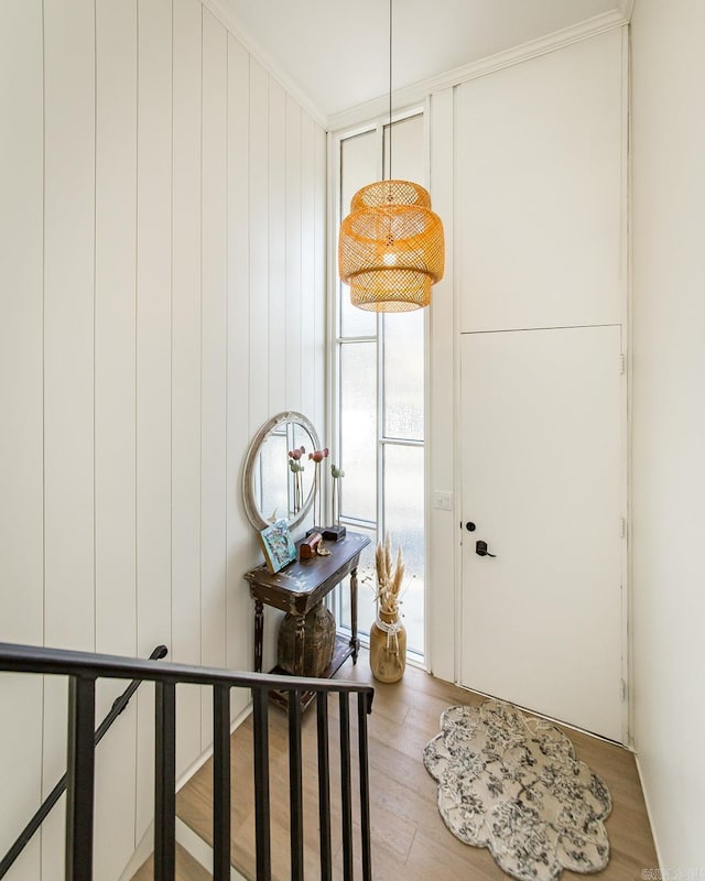 doorway with light hardwood / wood-style flooring and crown molding